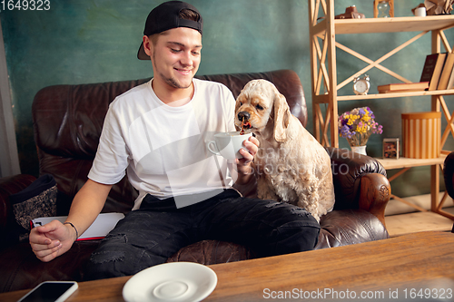 Image of Two best friends young man and American Cocker Spaniel cream colour drink tea at home.