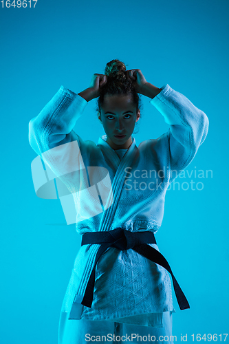 Image of Portrait of professional female judoist isolated on blue studio background in neon light. Healthy lifestyle, sport concept.