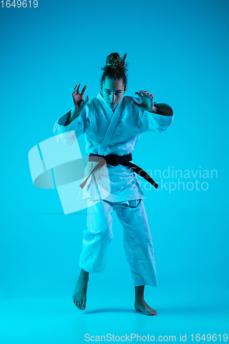 Image of Young girl professional judoist isolated on blue studio background in neon light. Healthy lifestyle, sport concept.