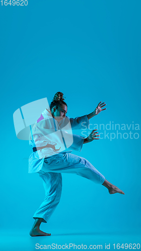 Image of Young girl professional judoist isolated on blue studio background in neon light. Healthy lifestyle, sport concept.