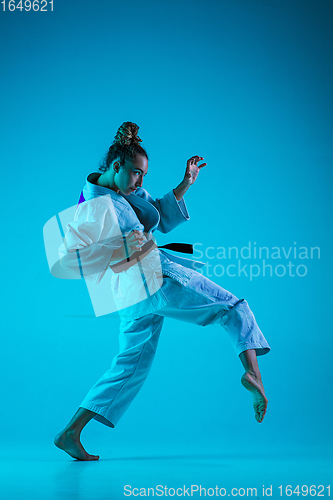 Image of Young girl professional judoist isolated on blue studio background in neon light. Healthy lifestyle, sport concept.