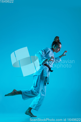 Image of Young girl professional judoist isolated on blue studio background in neon light. Healthy lifestyle, sport concept.