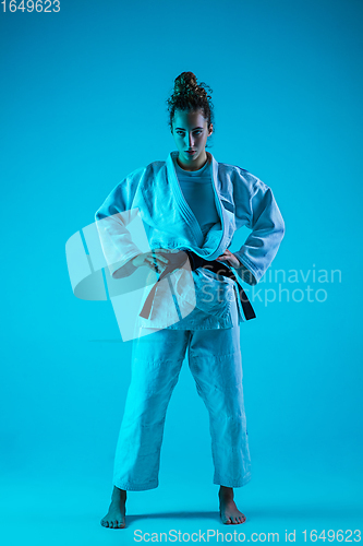 Image of Portrait of professional female judoist isolated on blue studio background in neon light. Healthy lifestyle, sport concept.