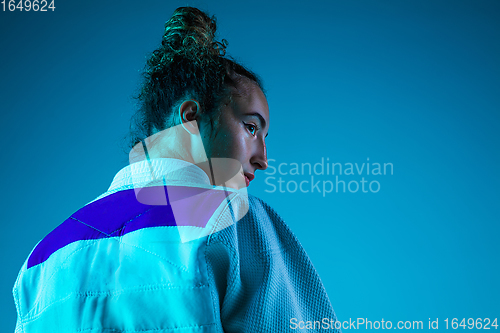 Image of Portrait of professional female judoist isolated on blue studio background in neon light. Healthy lifestyle, sport concept.