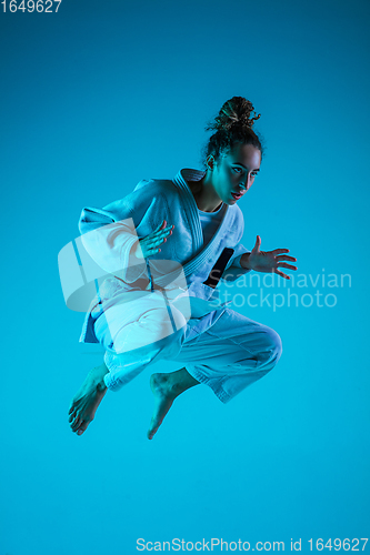 Image of Young girl professional judoist isolated on blue studio background in neon light. Healthy lifestyle, sport concept.