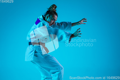 Image of Young girl professional judoist isolated on blue studio background in neon light. Healthy lifestyle, sport concept.