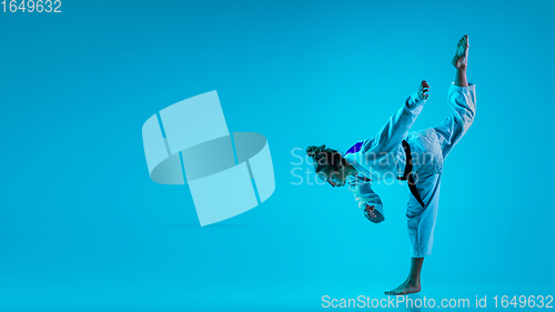 Image of Professional female judoist posing isolated on blue studio background in neon light. Flyer for ad, design.