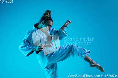 Image of Young girl professional judoist isolated on blue studio background in neon light. Healthy lifestyle, sport concept.