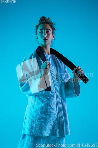 Image of Young girl professional judoist isolated on blue studio background in neon light. Healthy lifestyle, sport concept.