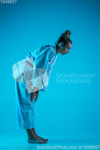 Image of Professional female judoist training isolated on blue studio background in neon light. Healthy lifestyle, sport concept.