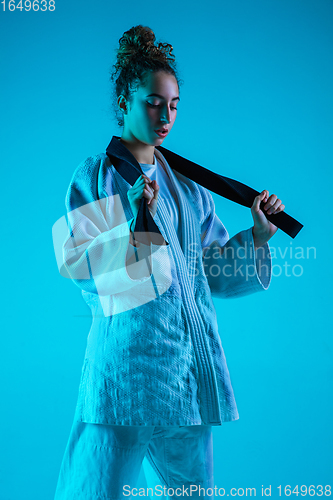 Image of Young girl professional judoist isolated on blue studio background in neon light. Healthy lifestyle, sport concept.