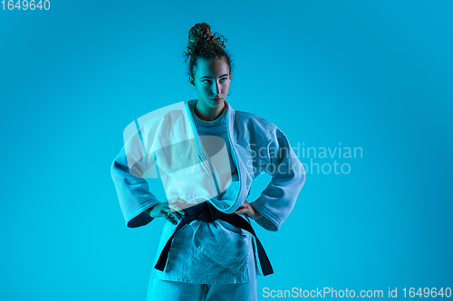 Image of Portrait of professional female judoist isolated on blue studio background in neon light. Healthy lifestyle, sport concept.