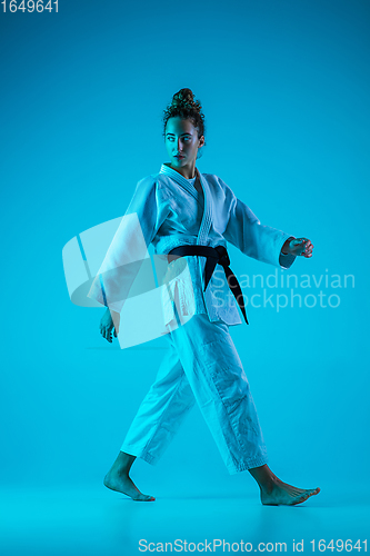 Image of Professional female judoist posing isolated on blue studio background in neon light. Healthy lifestyle, sport concept.