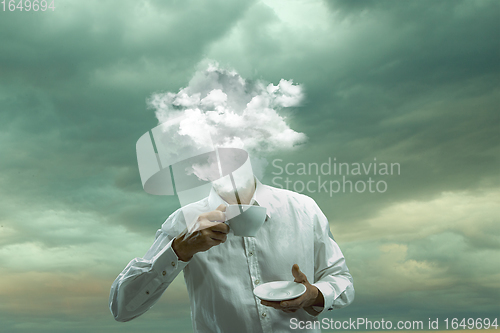 Image of Contemporary art collage. Male body of model with head full of smoke about sky and clouds drinking tea.