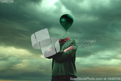 Image of Contemporary art collage. Male body of model with head like green ballon on blue grey background. Creativity, brain concept .