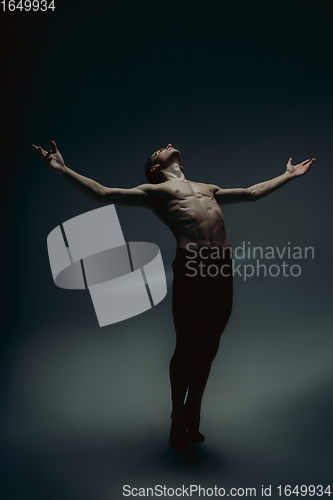 Image of Young and graceful ballet dancer in minimal black style isolated on black studio background