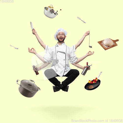 Image of Handsome multi-armed cooker levitating isolated on yellow studio background with equipment