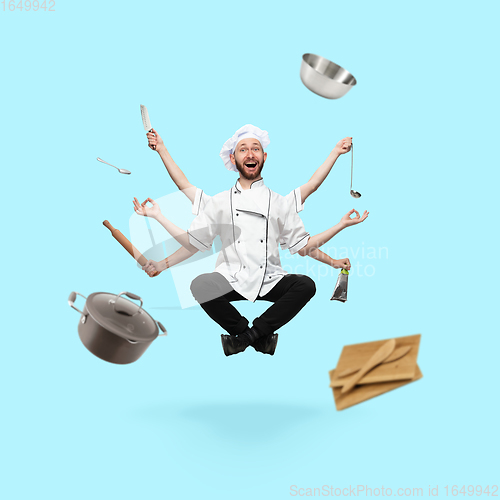Image of Happy handsome multi-armed cooker levitating isolated on blue studio background with equipment