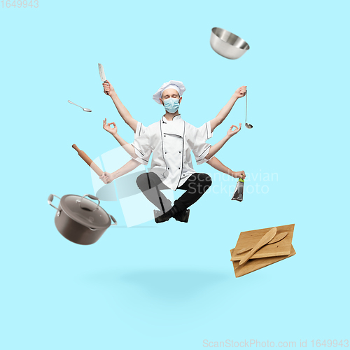 Image of Young handsome multi-armed cooker in face mask levitating isolated on blue studio background with equipment