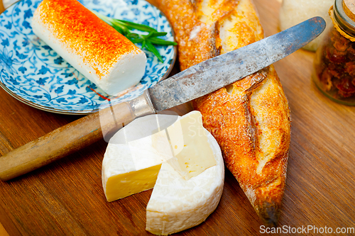 Image of French cheese and fresh  baguette on a wood cutter