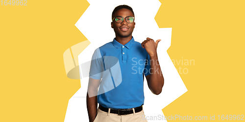 Image of Young african-american man\'s portrait isolated on yellow studio background, facial expression. Magazine style concept.