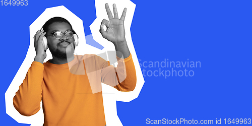 Image of Young african-american man\'s portrait isolated on blue studio background, facial expression. Magazine style concept.