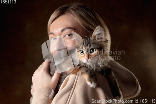 Image of A small purebred kitten sitting on the shoulder of a young woman isolated on colored background. Flyer for ad, design.