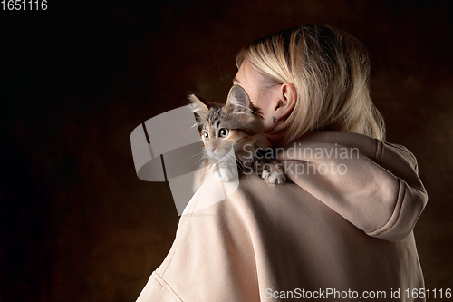 Image of A small purebred kitten sitting on the shoulder of a young woman isolated on colored background. Flyer for ad, design.
