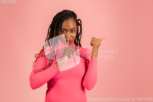 Image of Young african-american woman isolated on pink studio background, facial expression. Beautiful female half-lenght portrait with copyspace.