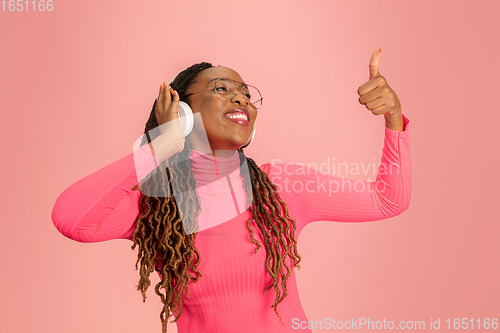 Image of Young african-american woman\'s portrait isolated on pink studio background, facial expression. Beautiful female half-lenght portrait with copyspace.