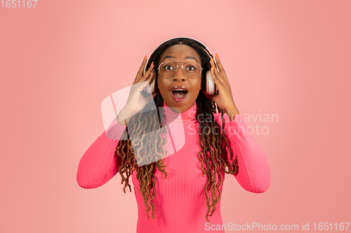 Image of Young african-american woman\'s portrait isolated on pink studio background, facial expression. Beautiful female half-lenght portrait with copyspace.