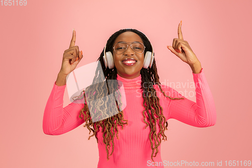 Image of Young african-american woman\'s portrait isolated on pink studio background, facial expression. Beautiful female half-lenght portrait with copyspace.