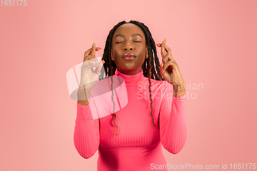Image of Young emotional african-american woman isolated on pink studio background, facial expression. Half-lenght portrait with copyspace.