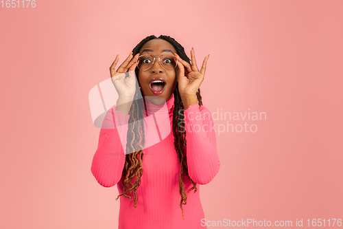 Image of Young emotional african-american woman isolated on pink studio background, facial expression. Half-lenght portrait with copyspace.