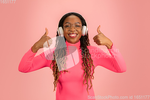 Image of Young african-american woman\'s portrait isolated on pink studio background, facial expression. Beautiful female half-lenght portrait with copyspace.