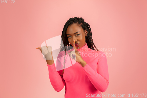Image of Young african-american woman isolated on pink studio background, facial expression. Beautiful female half-lenght portrait with copyspace.