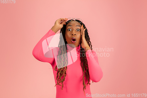 Image of Young emotional african-american woman isolated on pink studio background, facial expression. Half-lenght portrait with copyspace.