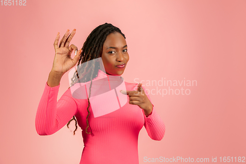 Image of Portrait of young african-american woman isolated on pink studio background, facial expression. Beautiful female half-lenght portrait with copyspace.