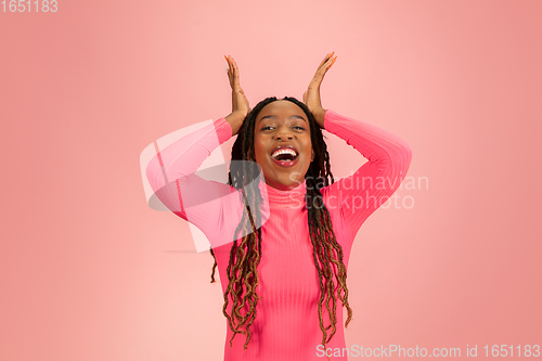 Image of Happy emotional african-american woman isolated on pink studio background, facial expression. Half-lenght portrait with copyspace.