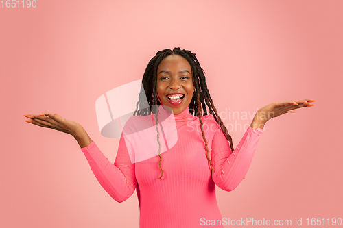 Image of Happy emotional african-american woman isolated on pink studio background, facial expression. Half-lenght portrait with copyspace.