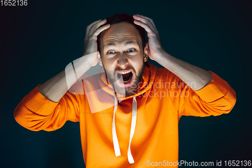 Image of Close up portrait of crazy scared and shocked man isolated on dark background