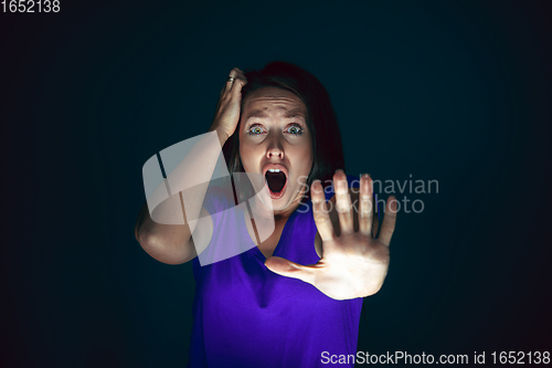 Image of Close up portrait of young crazy scared and shocked woman isolated on dark background