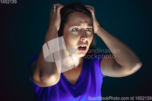 Image of Close up portrait of young crazy scared and shocked woman isolated on dark background