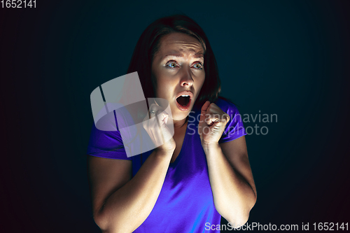 Image of Close up portrait of young crazy scared and shocked woman isolated on dark background