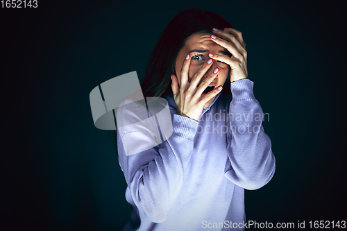 Image of Close up portrait of young crazy scared and shocked woman isolated on dark background