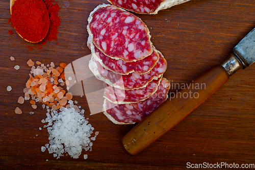 Image of traditional Italian salame cured sausage sliced on a wood board