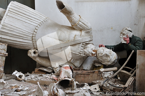 Image of broken statue and man with plaster mask fragment