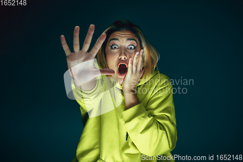 Image of Close up portrait of young crazy scared and shocked woman isolated on dark background