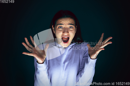 Image of Close up portrait of young crazy scared and shocked woman isolated on dark background