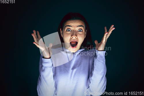 Image of Close up portrait of young crazy scared and shocked woman isolated on dark background